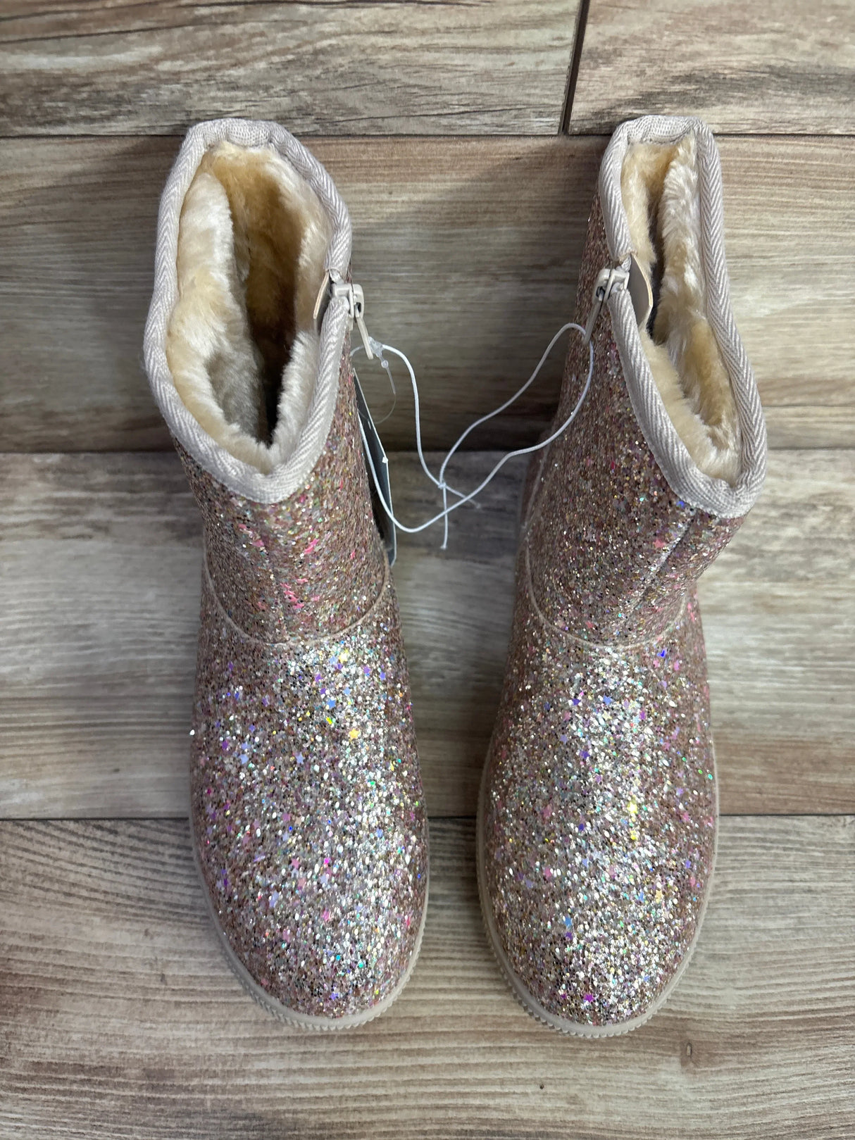 Sparkly glitter pink kids winter boots with faux fur lining on wood background