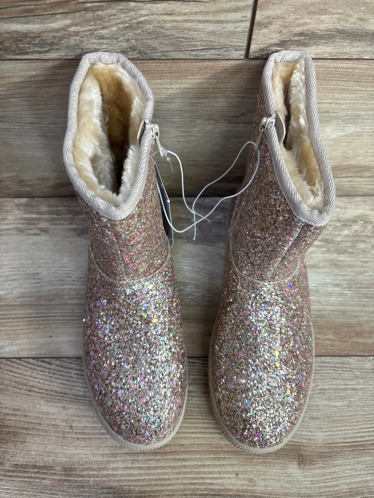 Top view of Cat & Jack Holland shearling-style kids boots showing glittery gold exterior and faux-shearling lining on wood background