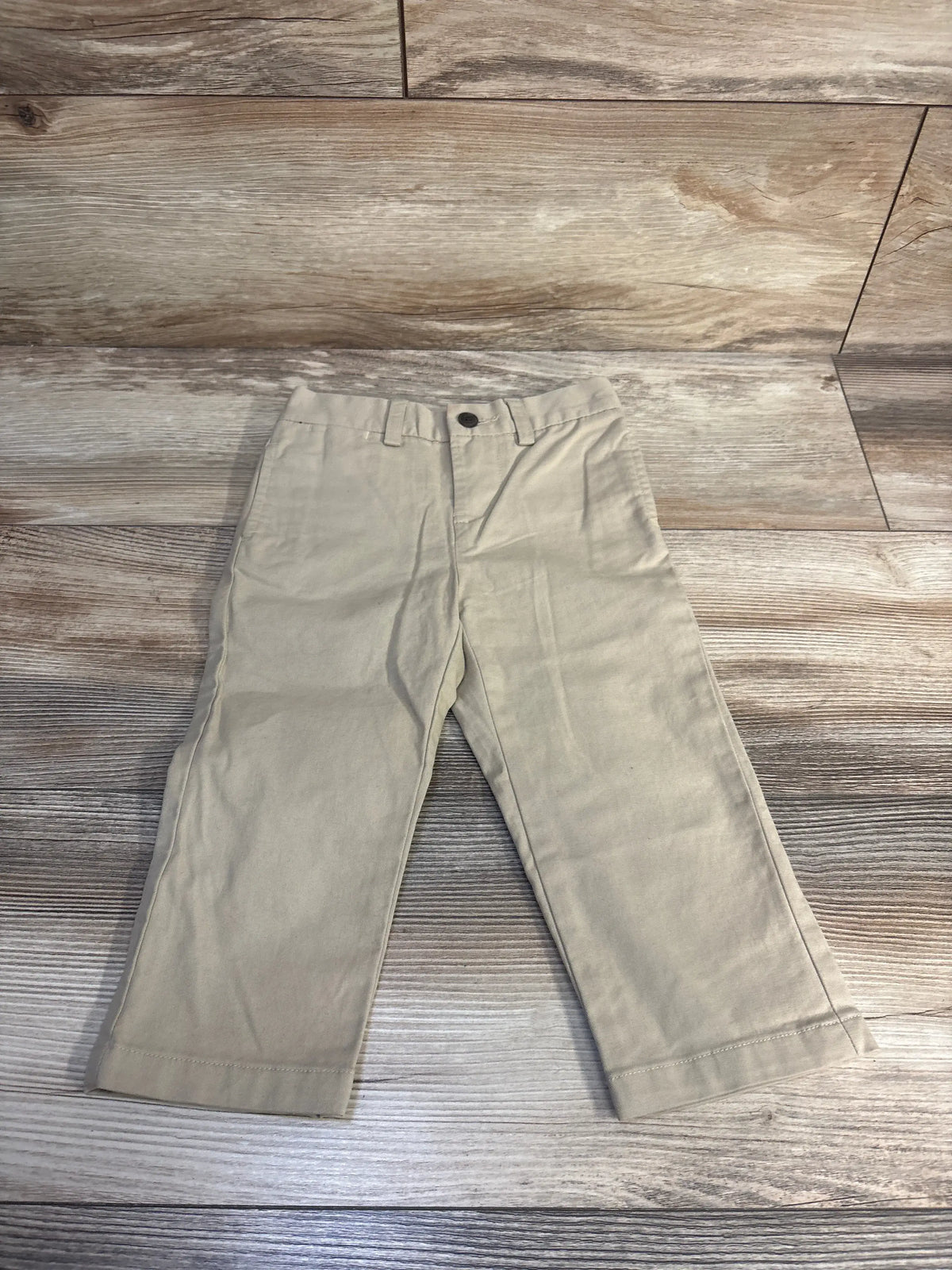 Front view of Ralph Lauren khaki flat front chinos showcasing belt loops, button closure, and straight legs on wood grain