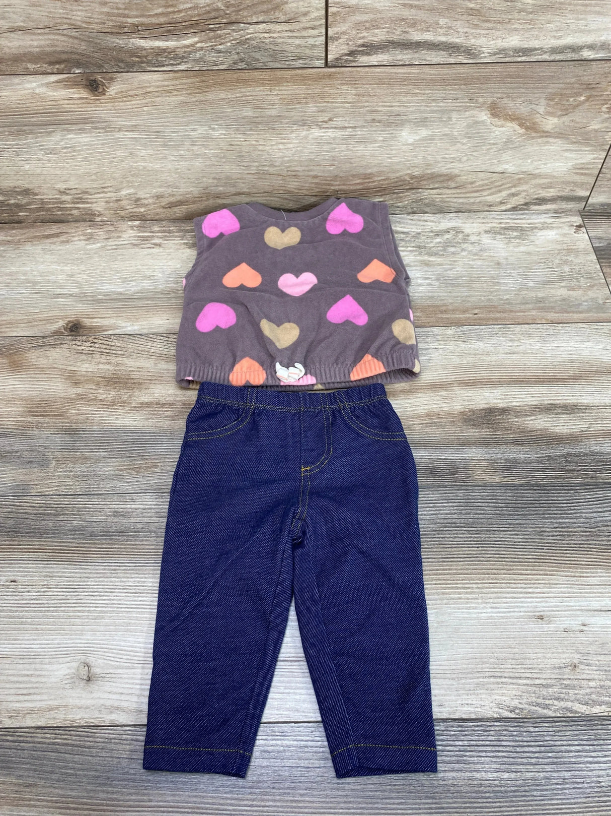 Flat lay of Carter's 2pc fleece vest and leggings, 6M, brown heart-print vest and dark leggings on wood background