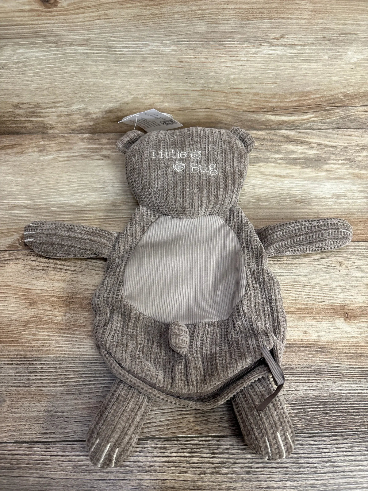 Top view of Little Bug Bev bear lovie showing brown corduroy, embroidered Little Bug on head and ribbed tummy on wood