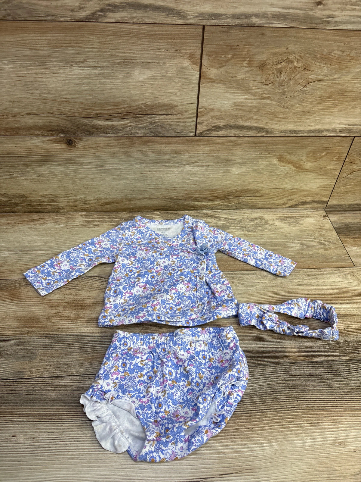 Top-down view of blue floral 3-piece kimono set with wrap top, bloomers, and headband on wood flooring