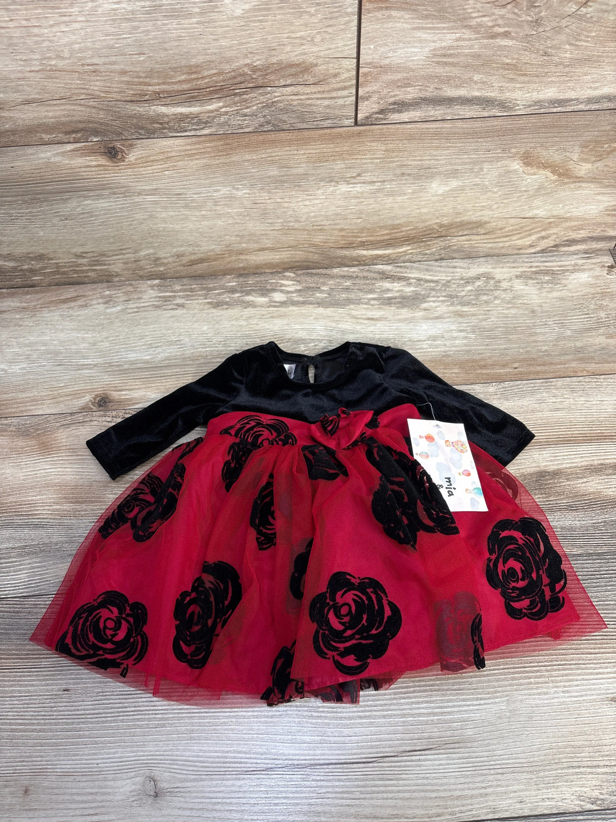 Black long-sleeve top baby dress with red tulle skirt and black rose patterns on wooden floor
