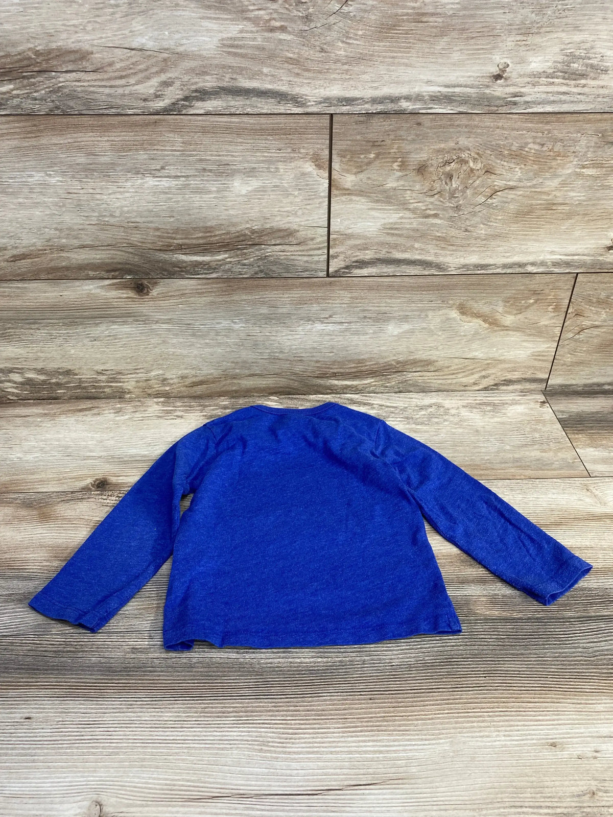 Back view of Children’s Place blue long-sleeve toddler shirt showing crew neckline and plain knit fabric on wood plank background