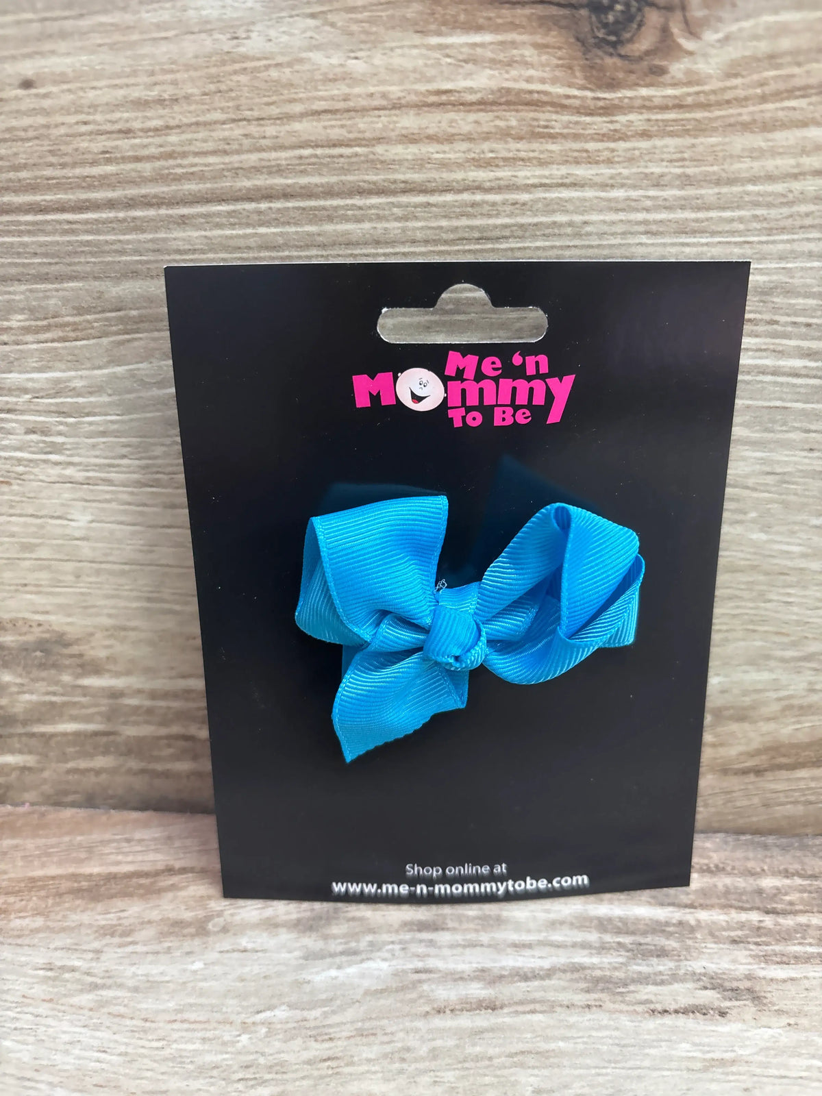 Front view of a blue solid hair bow showcasing its looped bow design on a black display card
