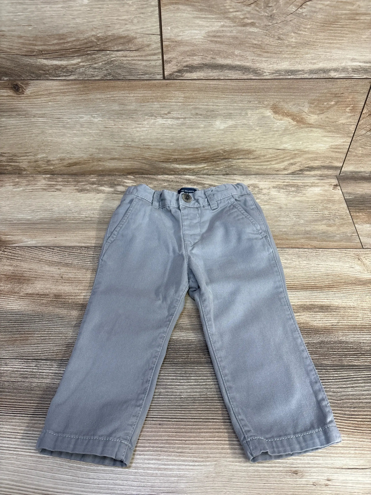 Front view of Children’s Place grey jeans, size 12 to 18 months, showcasing adjustable waistband on a wood-look floor