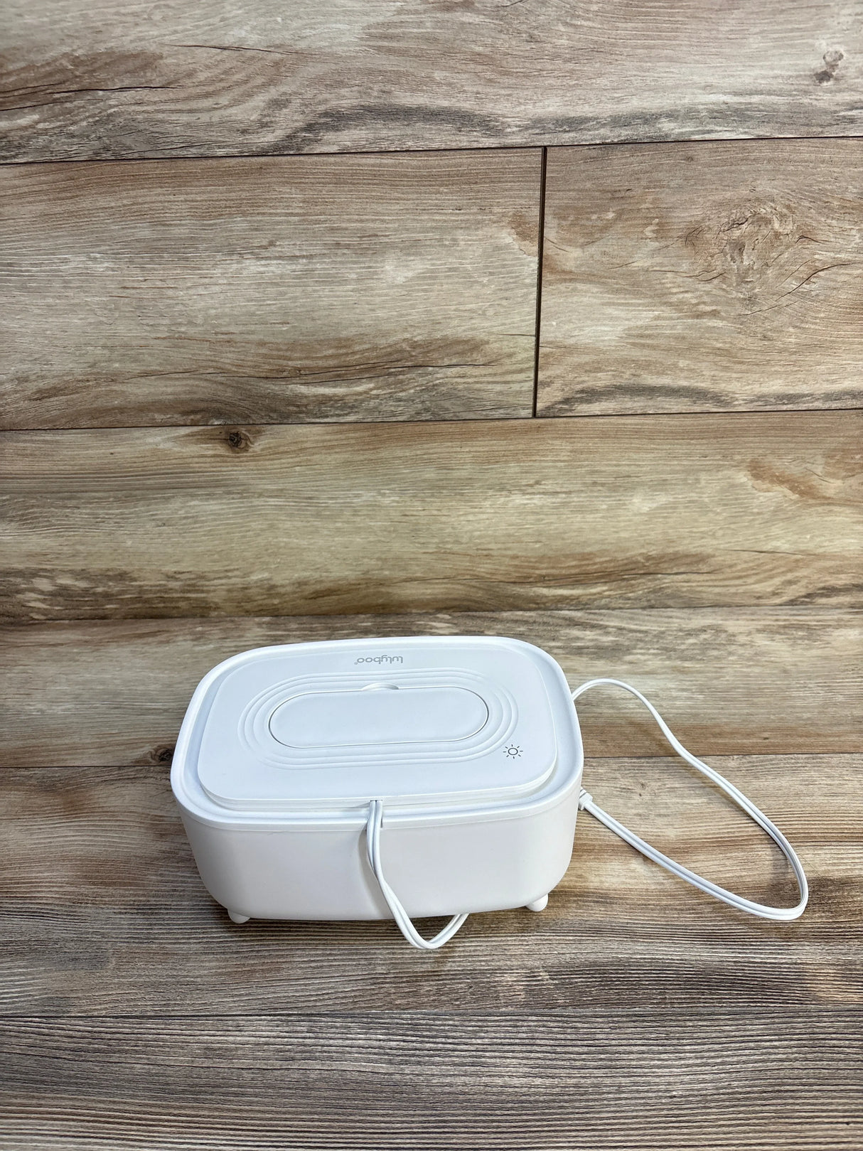 Angled view of Lulyboo wipe warmer and dispenser in white showing lid, power cord and indicator light on wood floor