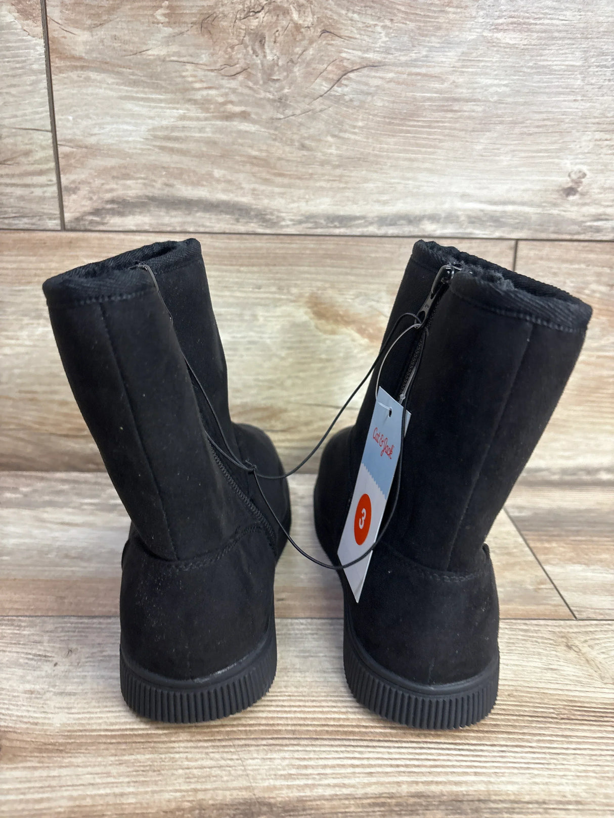 Children's black suede winter boots with side zippers and size 3 tag on wooden floor