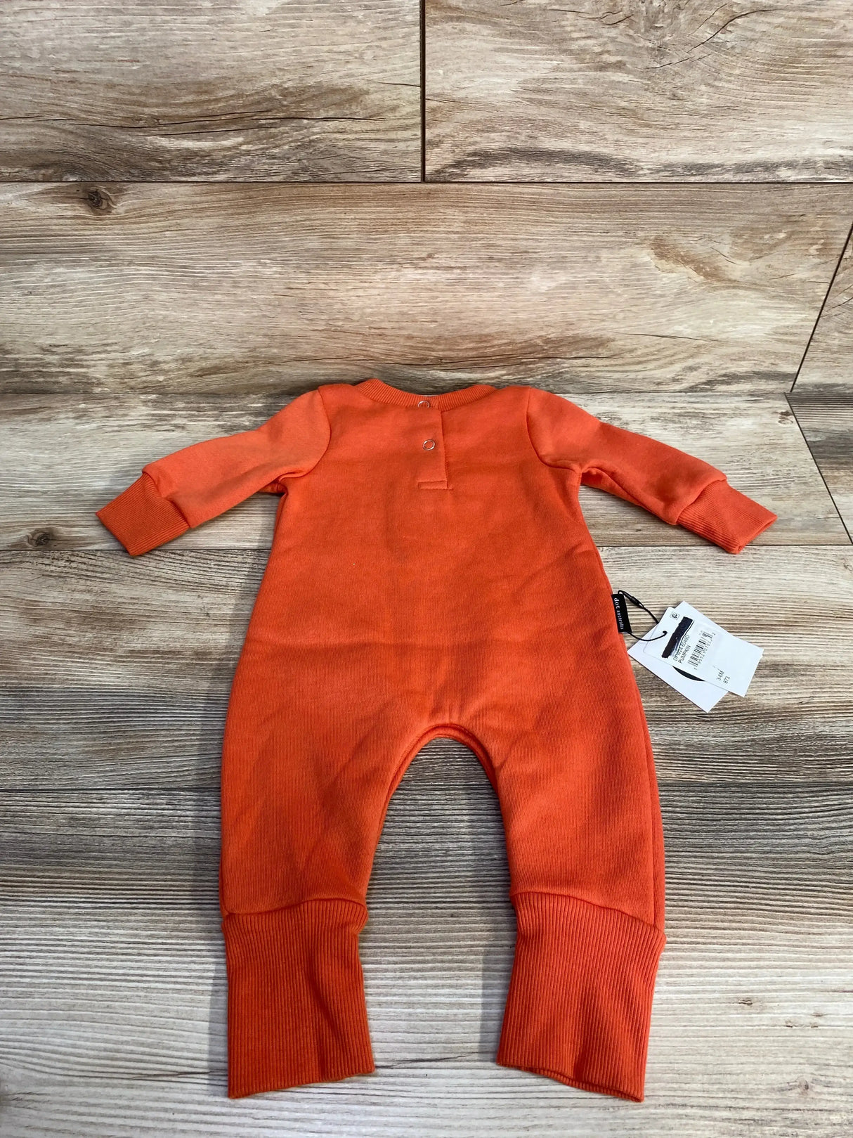 Orange baby onesie with long sleeves and ribbed cuffs, laid on wood floor, ideal for resale shopping.