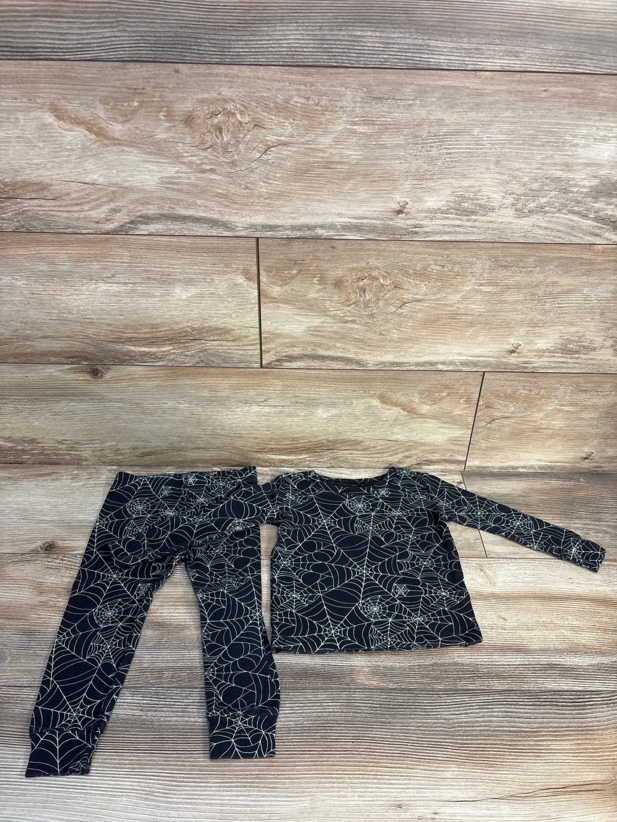 Flat lay of Old Navy black two piece pajama set showcasing a long sleeve top and pants with white spiderweb print