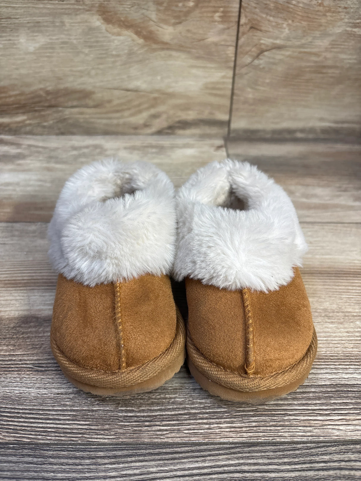 Front view of Wonder Nation brown toddler slippers showcasing plush white faux fur cuff on wood background