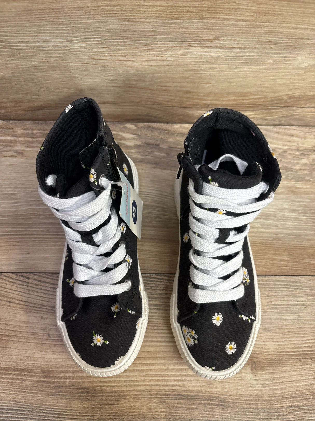 Top view of Cat and Jack Cora high-top kids sneakers in black with white daisy print and white laces on wood floor