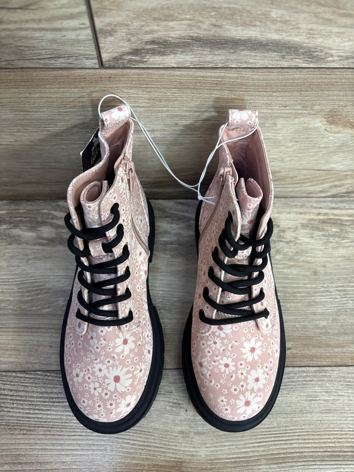 Pink floral toddler boots with black laces and thick soles on wood floor