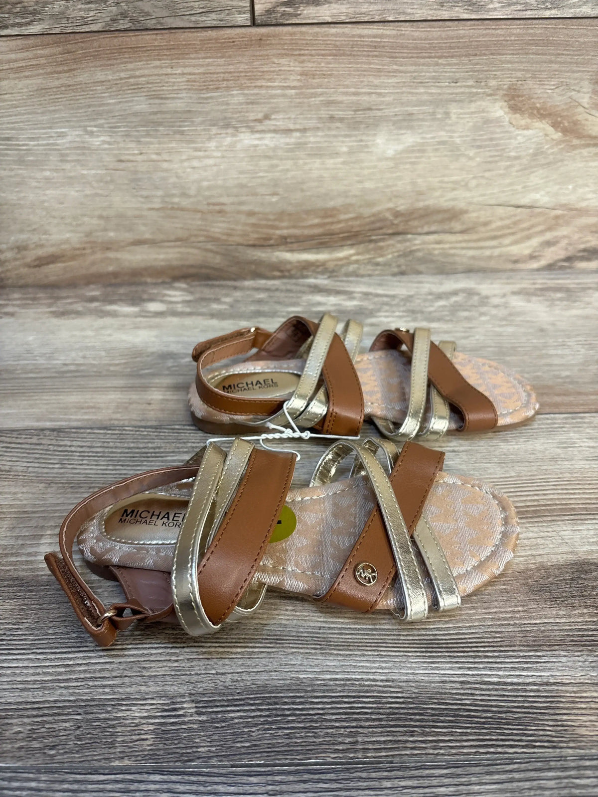 Kids' brown and gold strappy sandals with patterned insole, displayed on wood background