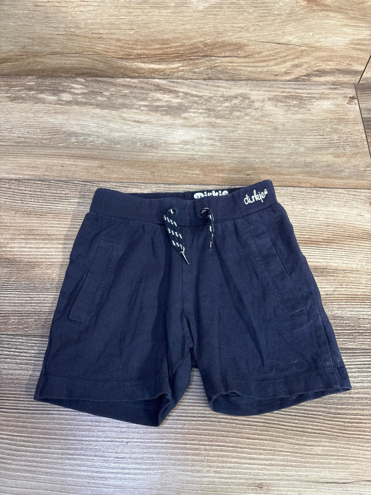 Front view of Dirkje navy drawstring shorts showcasing two side pockets and adjustable waist on a wood surface