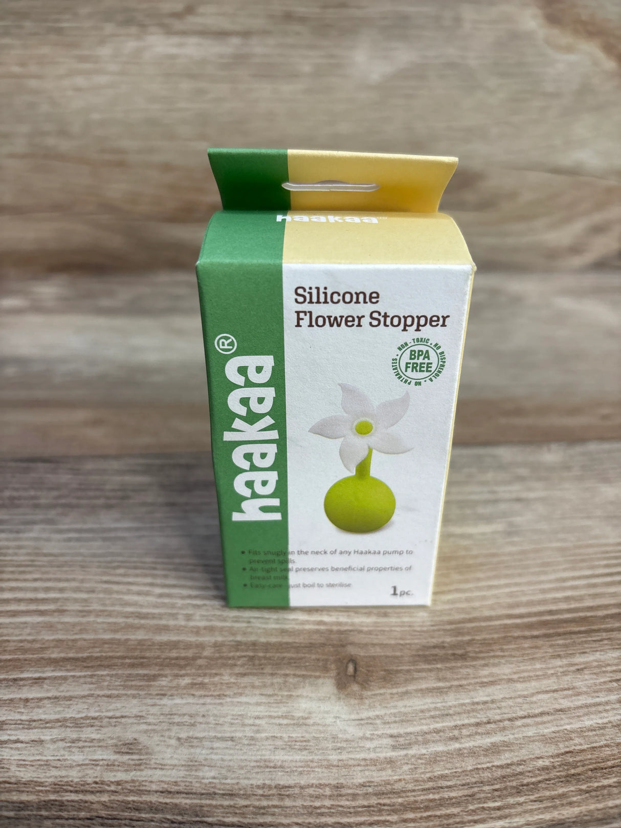 Haakaa Silicone Flower Stopper box on wooden surface, BPA free, green and yellow packaging