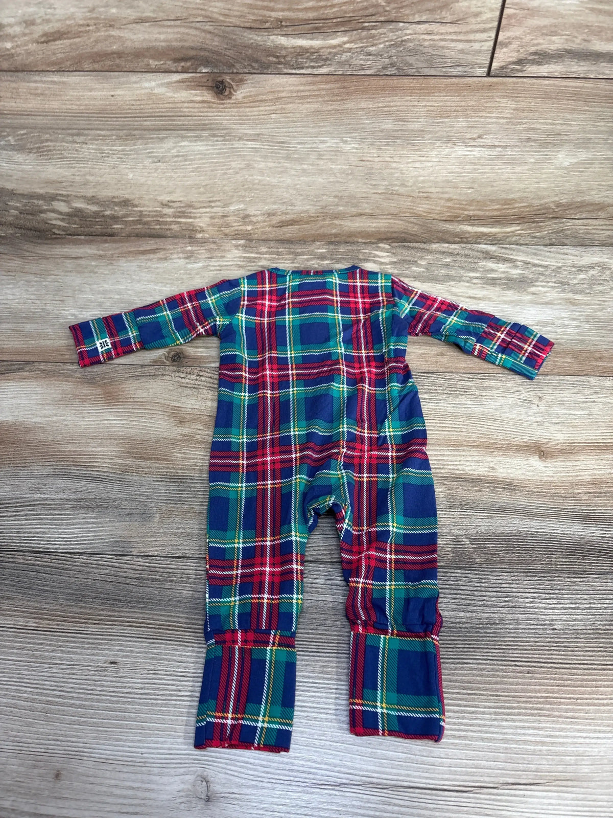 Back view of a red, green, and blue plaid baby onesie with long sleeves on a wooden floor