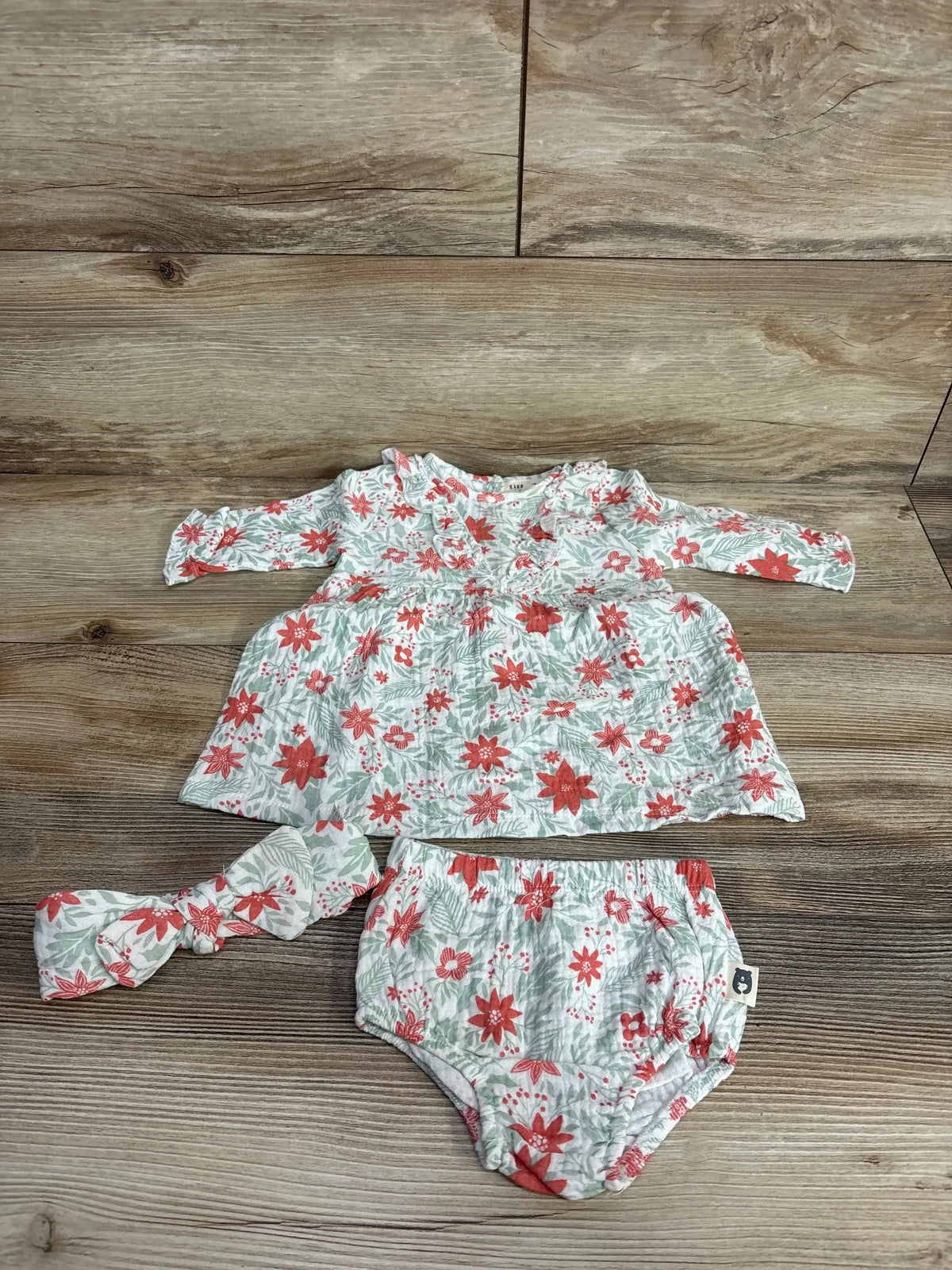 Floral baby girl dress set with matching headband and bloomers on wood background
