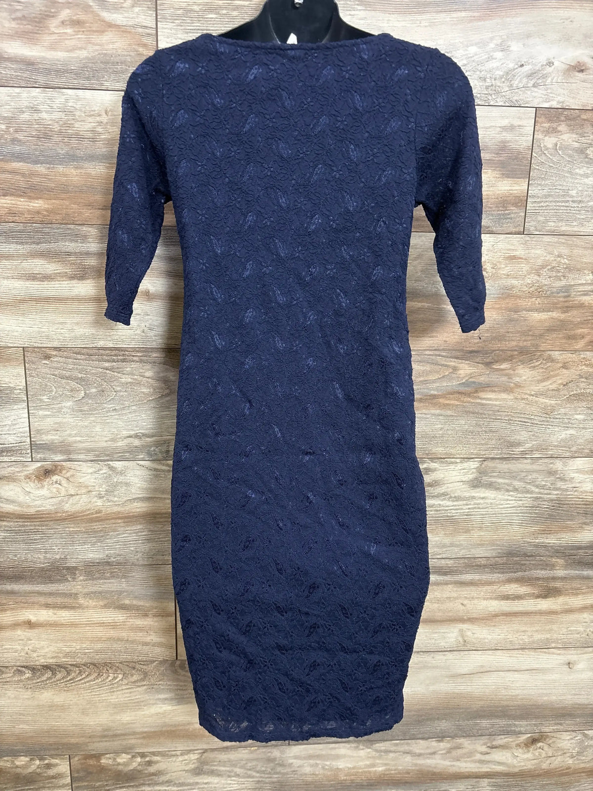 Front view of navy Pink Blush maternity fitted lace dress with 3/4 sleeves on hanger against wood background
