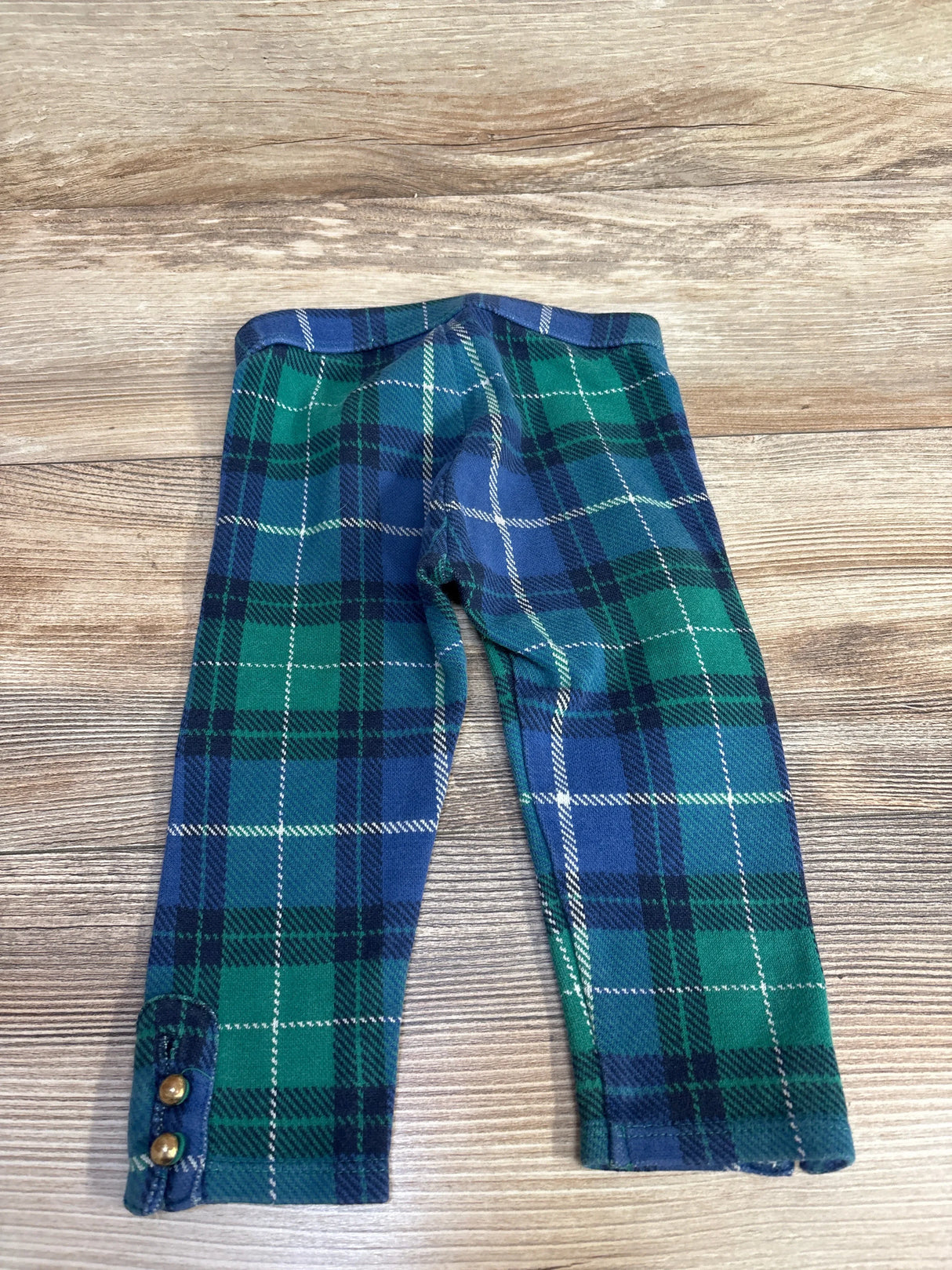 Flat lay of toddler Janie & Jack plaid pants, blue and green jacquard, button-cuff detail on wood background