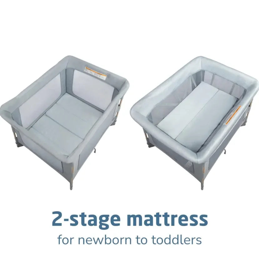 Angled view of Maxi-Cosi Swift playard in Classic Slate showing two-stage mattress for newborn and toddler on white background