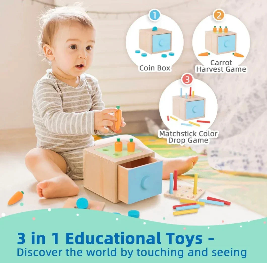 Three-quarter view of wooden Montessori toy box with open blue drawer, carrot pegs, and matchstick color-drop board with baby sitting on floor behind
