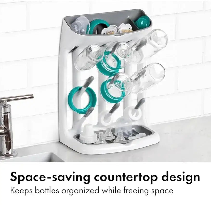Front of OXO Tot drying rack, Space-saving countertop design, with angled pegs holding bottles and tray for nipples on tile