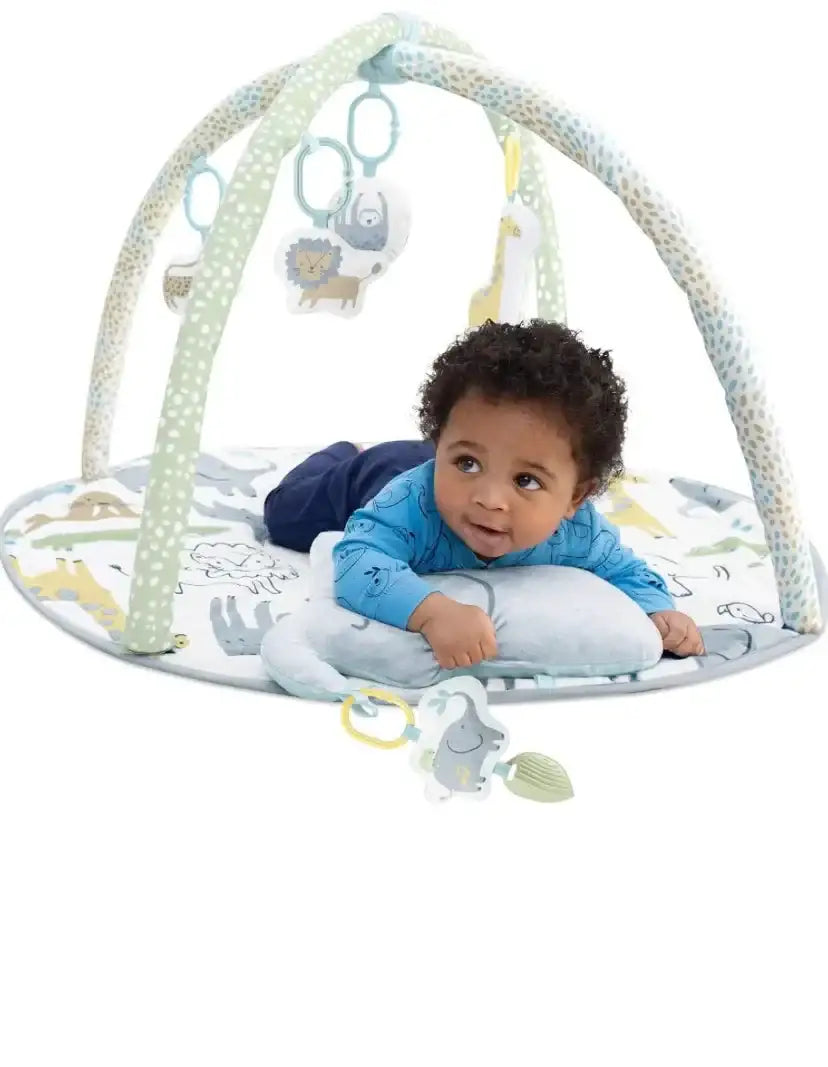 Front of Carter’s Safari play gym showing baby on padded round mat with hanging safari toys and pillow on white background