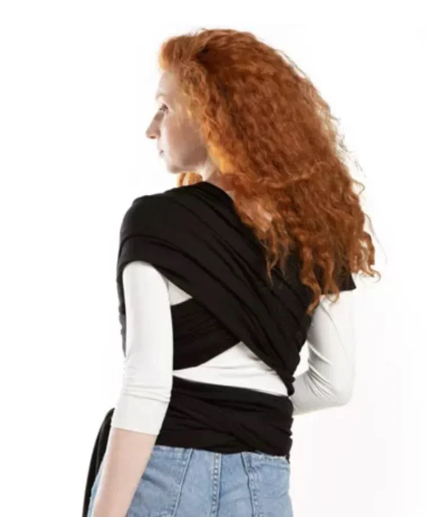 Woman wearing a black baby wrap carrier over a white shirt and jeans, shown from the back