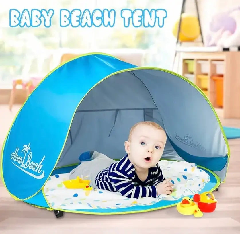 Front view of Monobeach pop-up baby beach tent in blue showing open shaded interior and padded play mat in a playroom