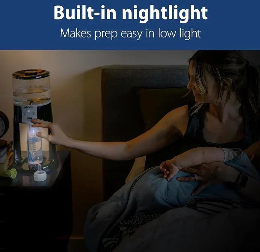 Mother holding baby in bed using baby bottle maker with built-in nightlight at night