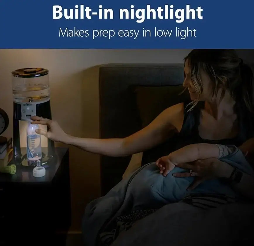 Mother holding baby in bed using baby bottle maker with built-in nightlight at night