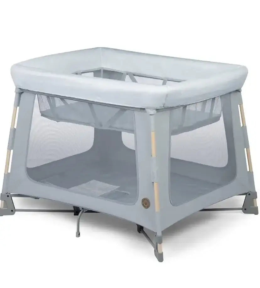 Angled front view of Maxi-Cosi Swift playard in Classic Slate showcasing mesh sides and padded top rail with white background