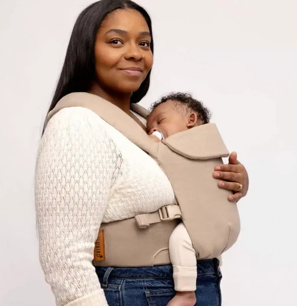 Front view of WildBird Aerial Carrier in Desert Lark showcasing padded straps and waist belt with sleeping baby
