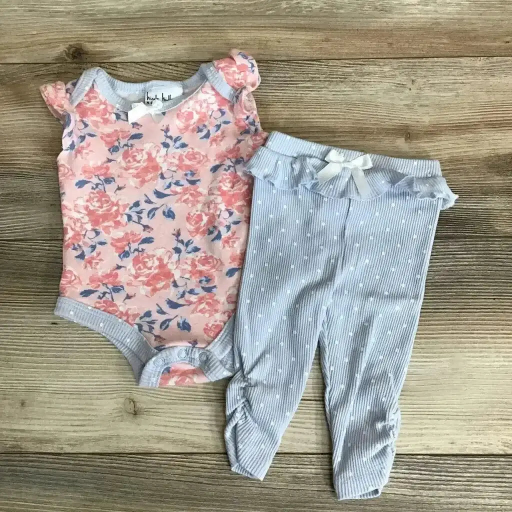 Flat lay of Nicole Miller 2-piece floral baby outfit: pink bodysuit and blue striped ruffle-waist leggings on wood