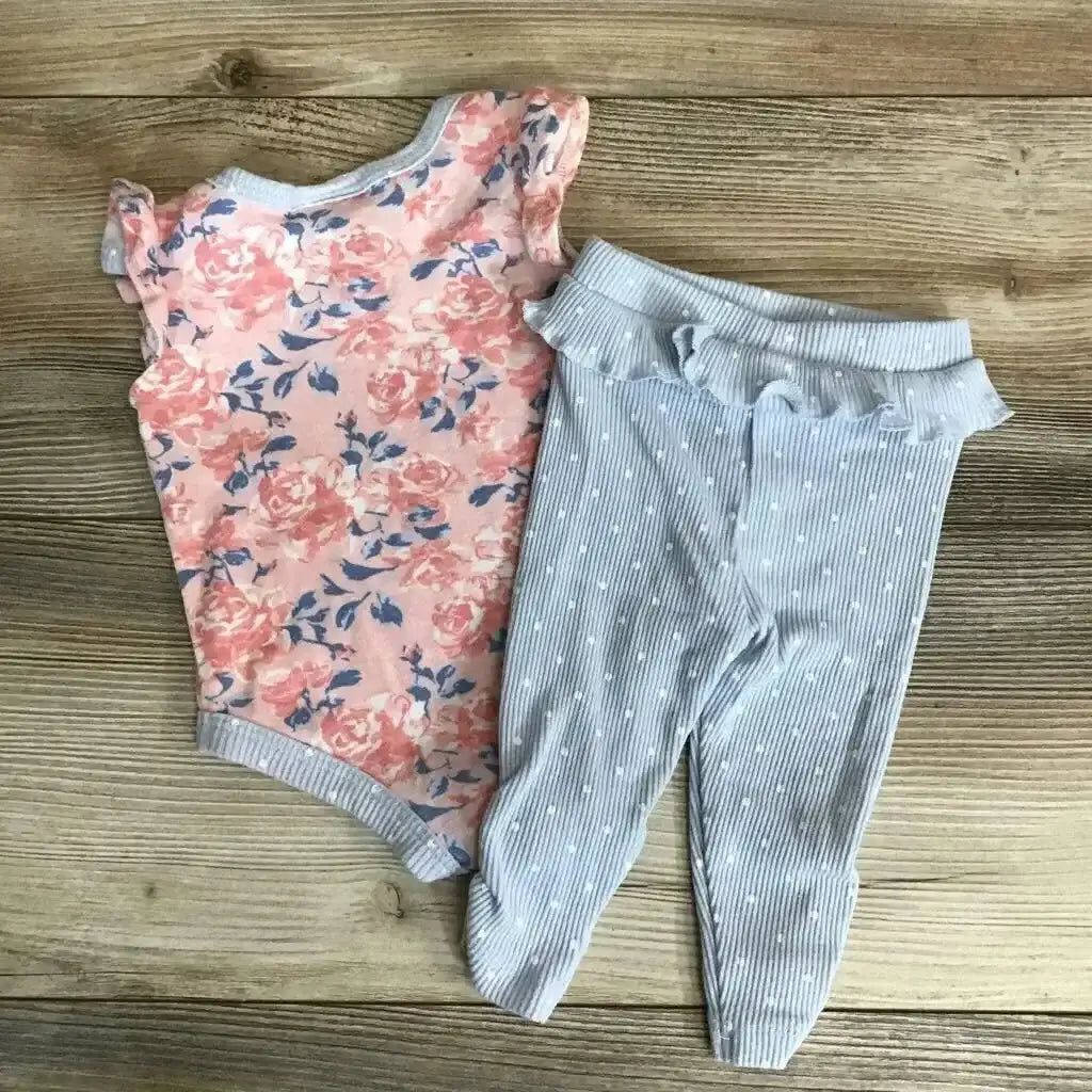 Flat lay of pink floral bodysuit and light gray ribbed footed pants showcasing rose print and ruffle waist on wood background