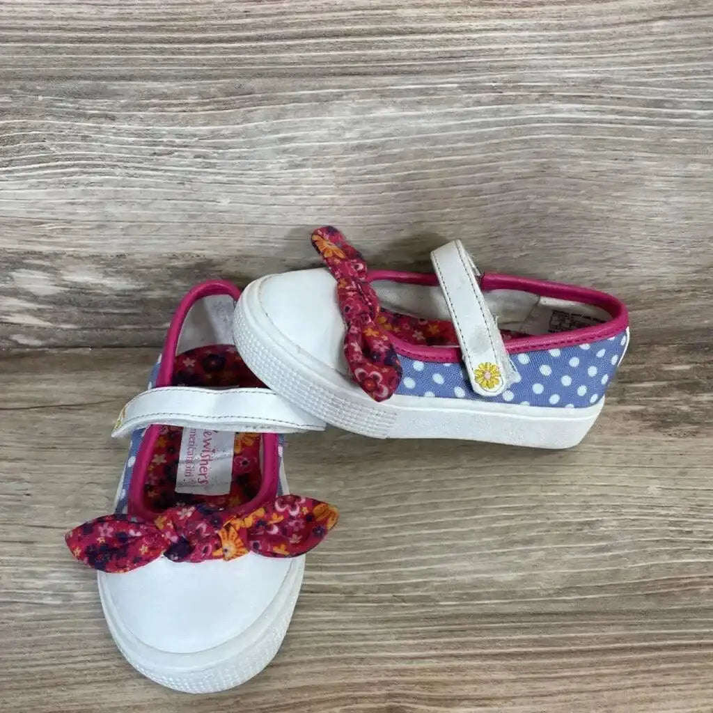 Angled view of American Girl Wellie Wishers polka-dot shoes size 5C with floral bow and Mary Jane strap on wood background