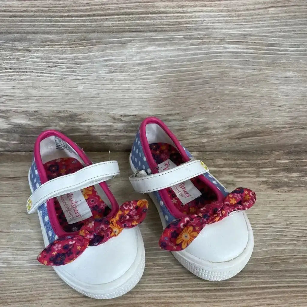 Front view of Wellie Wishers shoes size 5c with white toe, purple polka-dot sides and floral bows on wood background