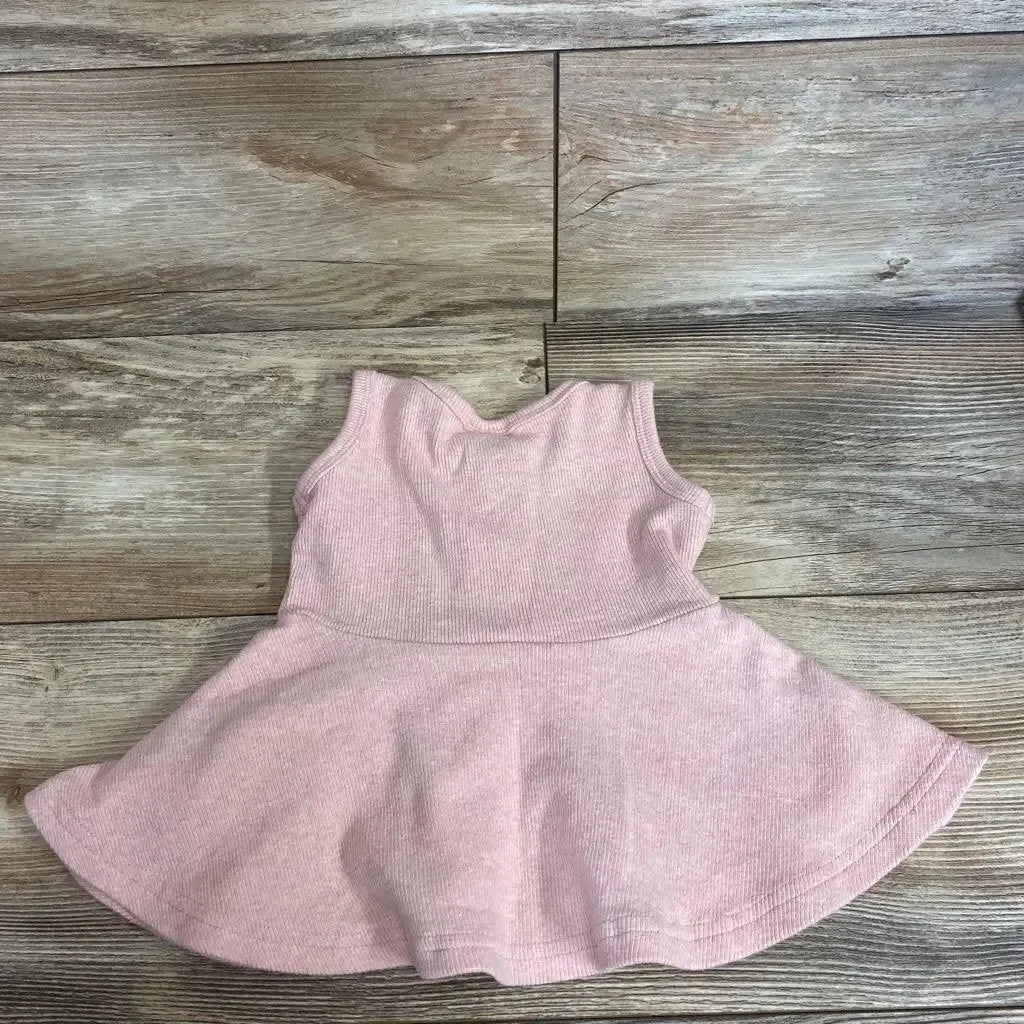 Flat-lay of blush ribbed baby twirl dress (0-3m) showcasing sleeveless ribbed bodice and flared skirt on wood plank background