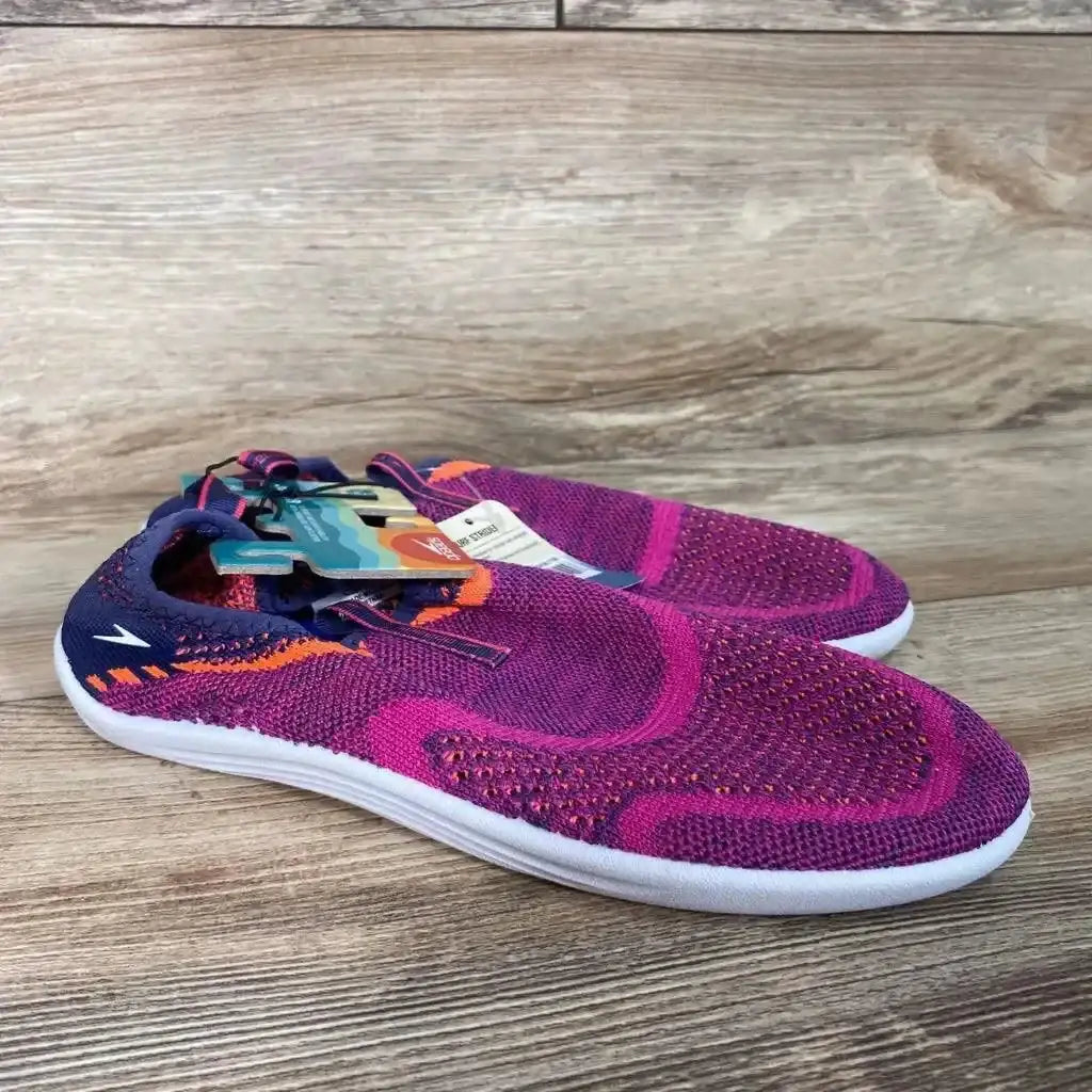 Three-quarter view of fuchsia Speedo Junior Surf Strider water shoes size 4/5Y showing knit upper, slip-on heel with pull tab and white sole on wood background