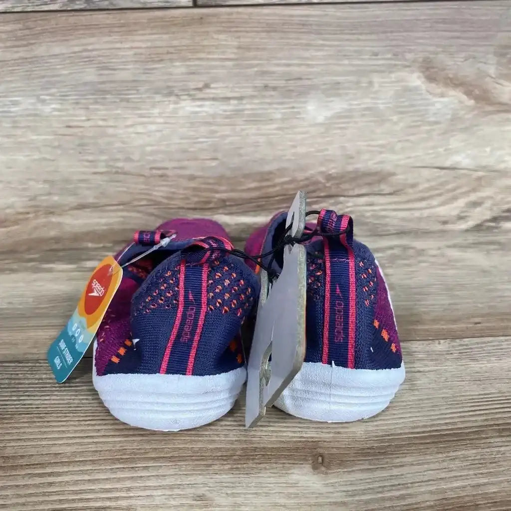 Rear view of Speedo Junior Surf Strider water shoes showing navy and fuchsia knit uppers and white soles on wood background