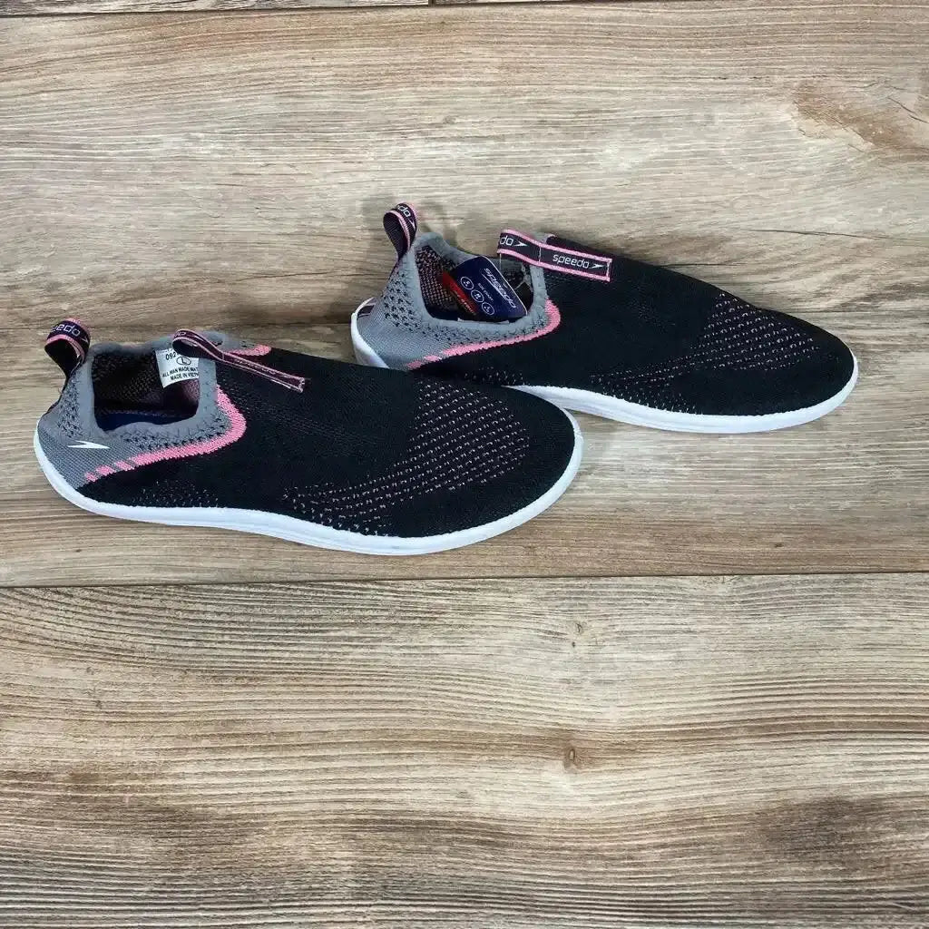 Angled view of Speedo Junior Surf Strider Water Shoes sz 9/10Y showcasing black mesh, pink accents, and white soles on wood