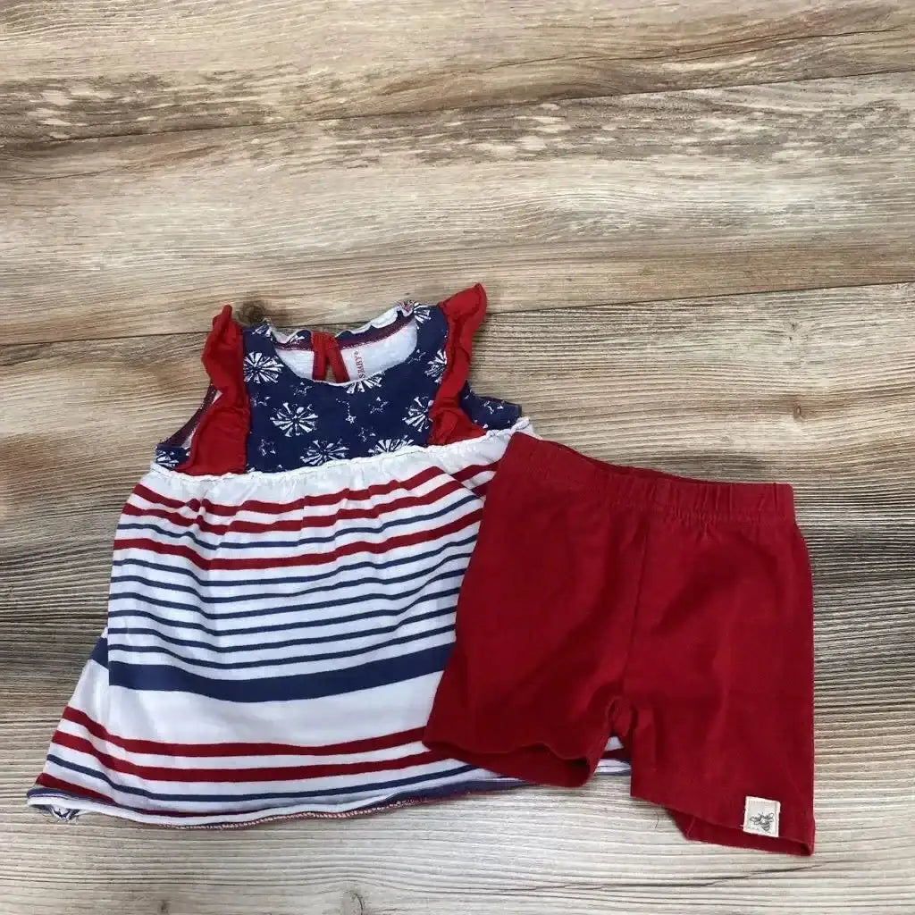 Flat-lay of 0-3M baby tunic and red shorts; tunic has navy floral yoke and red-and-white stripes on wood background