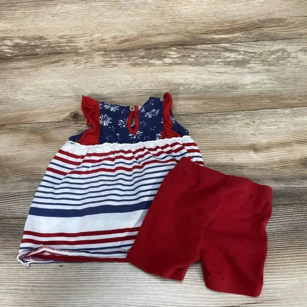 Flat lay of Burt's Bees baby tunic and shorts, red shorts and navy-and-white striped tunic on wood background