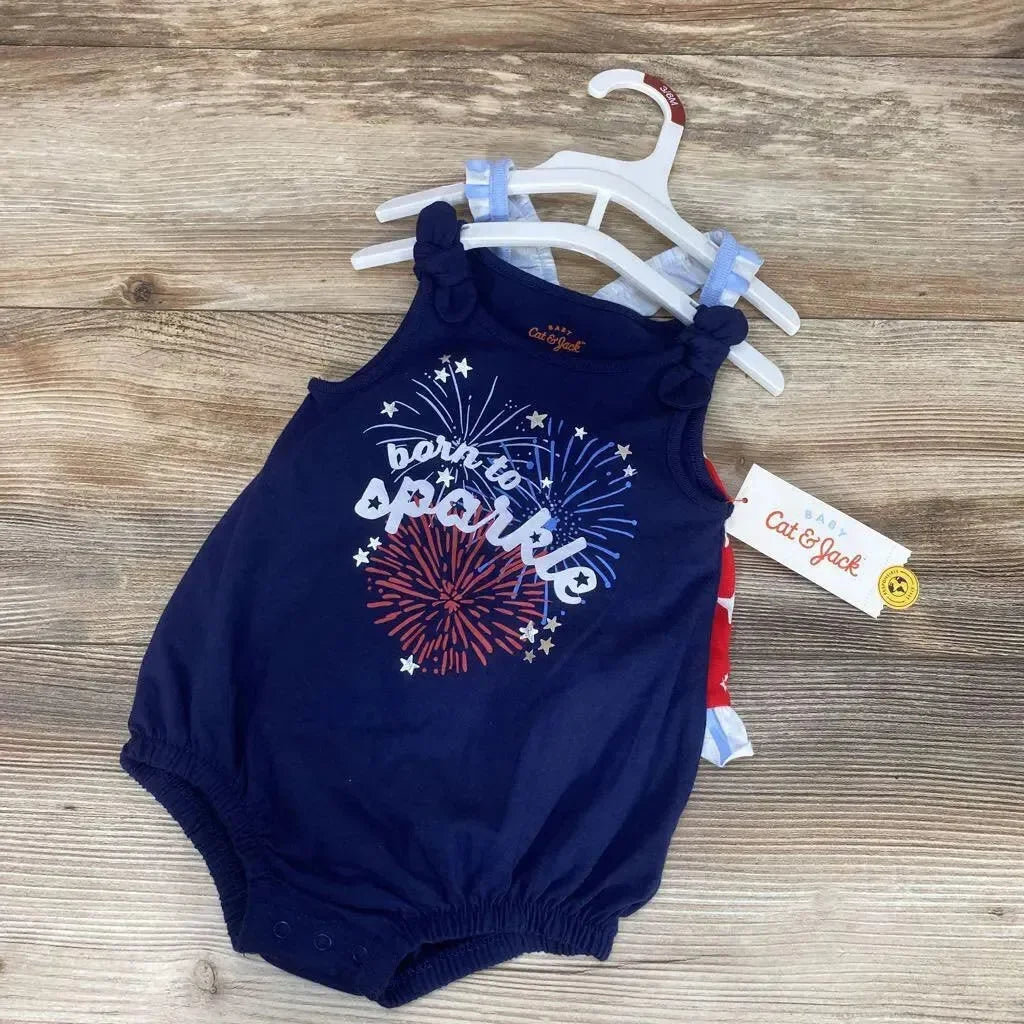 Flat-lay of navy baby romper (3–6M) showing Born to Sparkle fireworks print, knotted straps and snaps, on wood background