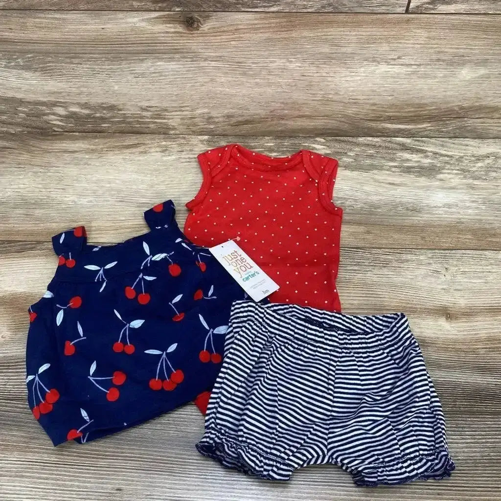 Flat lay of 3-piece 3M baby bodysuit set: navy cherry top, red polka-dot bodysuit, navy striped shorts on wood background