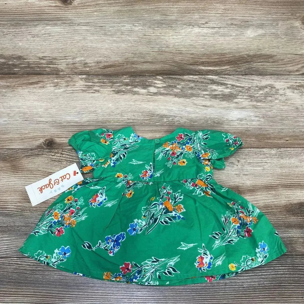 Flat lay of Cat and Jack newborn green floral short sleeve dress showcasing puff sleeves and gathered waist with wood plank background