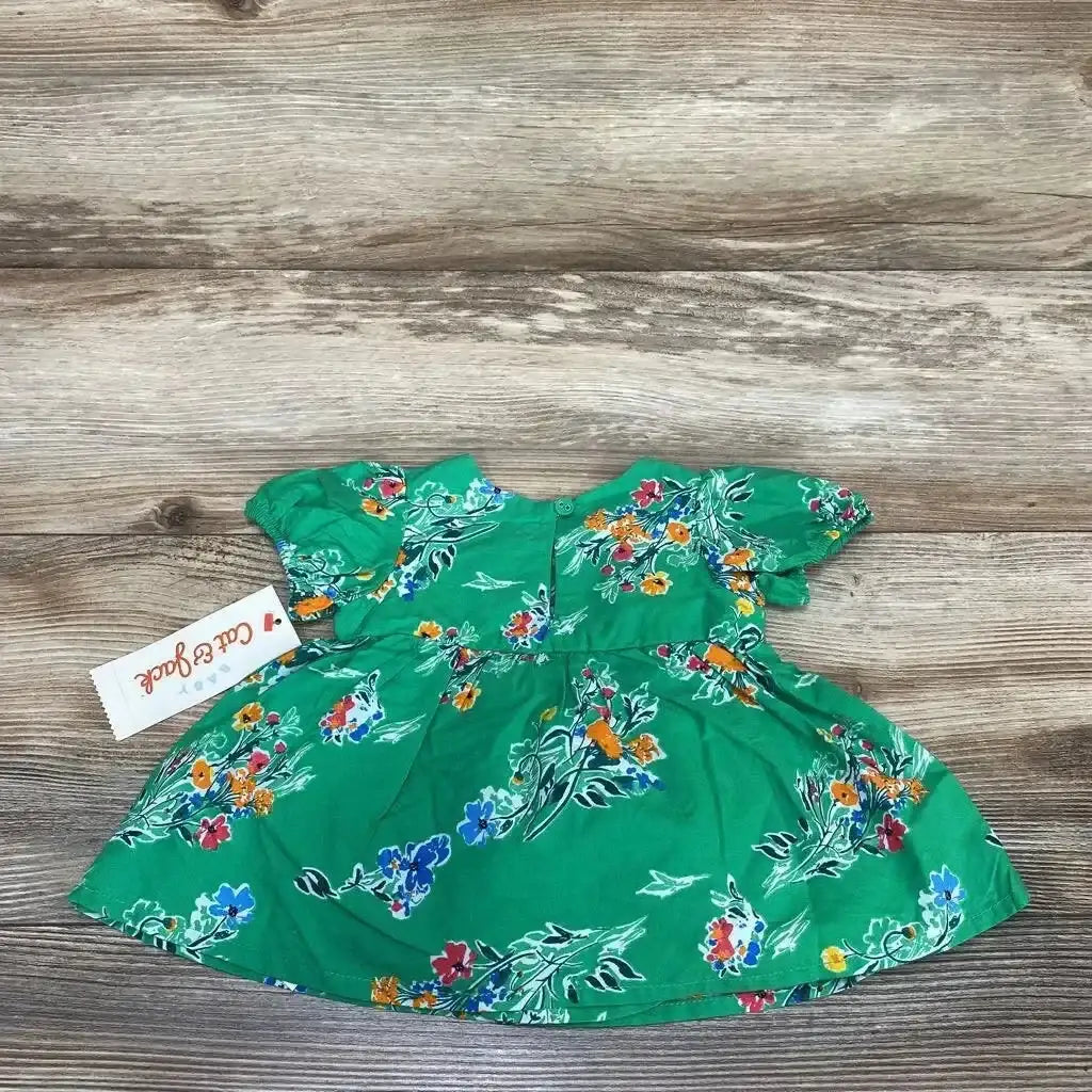 Flat lay of Cat and Jack newborn green floral short sleeve dress showcasing puff sleeves and gathered waist with wood plank background