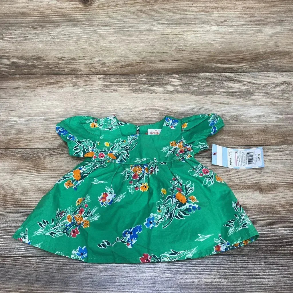 Flat lay of Cat & Jack newborn green floral short-sleeve dress with puff sleeves and gathered waist on wood background