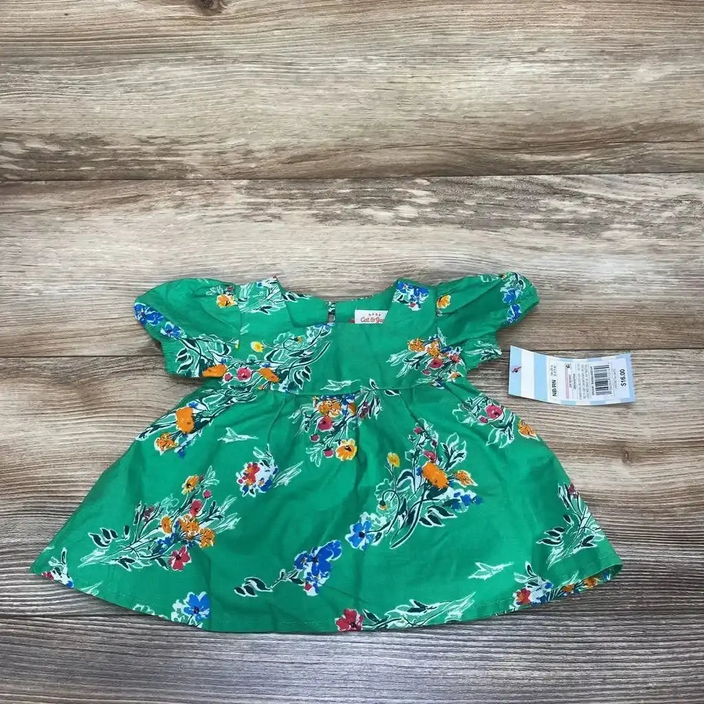 Flat lay of Cat & Jack newborn green floral short-sleeve dress with puff sleeves and gathered waist on wood background